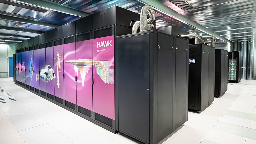 HPE-Supercomputer Hawk im HLRS. Hauptsächlich schwarzer Supercomputer mit blauen und rosa Elementen im offenen Raum stehend.